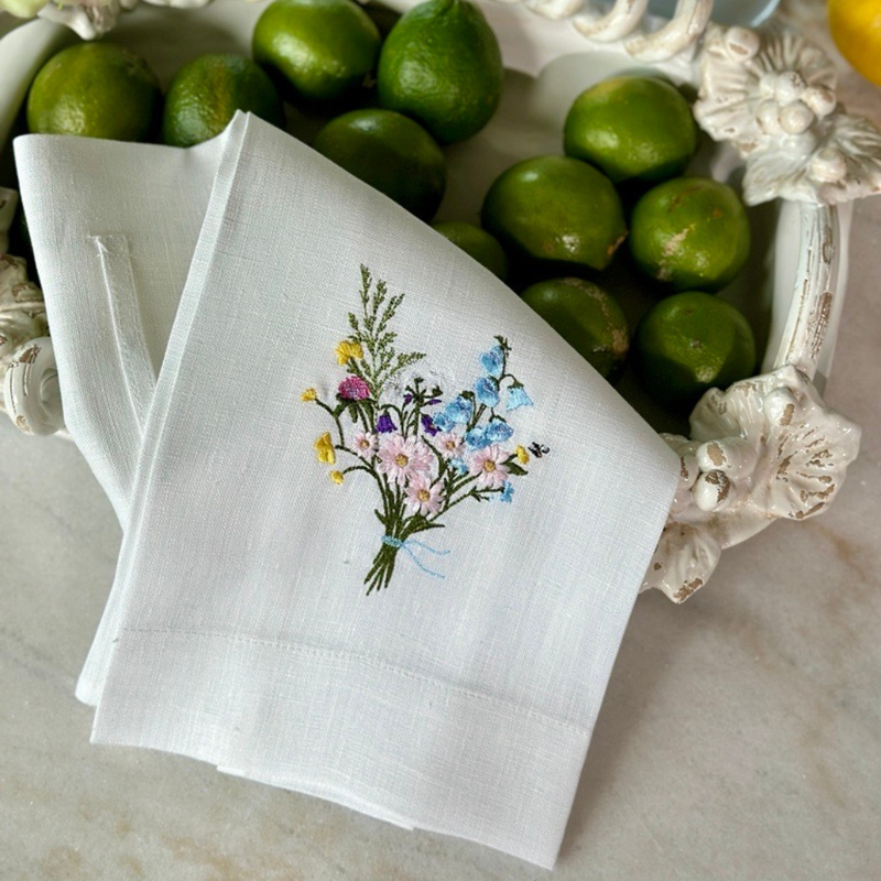 Arte Italica & Crown Linen Designs - Wildflower Bouquet Linen Towel: White (Multi), featuring embroidered wildflowers, displayed with limes on a white surface. Perfect for adding elegance to kitchen decor.