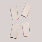 ATELIER SAUCIER - Macaw Burlap Napkins | Set of 4, featuring folded white napkins with vibrant trim, displayed elegantly to highlight texture and design.