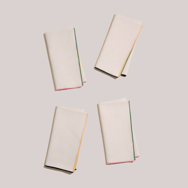 ATELIER SAUCIER - Macaw Burlap Napkins | Set of 4, featuring folded white napkins with vibrant trim, displayed elegantly to highlight texture and design.