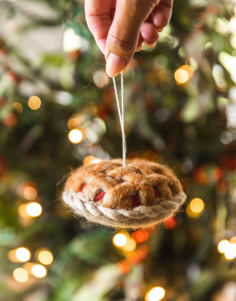 Farmhouse Pottery - Granny's Apple Pie Felt Ornament, handcrafted in Nepal, hangs on a Christmas tree, capturing festive charm in a cozy kitchen theme.