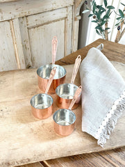 Coppermill Kitchen LLC - Coppermill Kitchen Vintage Inspired Measuring Cup set on rustic table, featuring custom-embossed copper finish with matching handles, accompanied by a linen cloth.