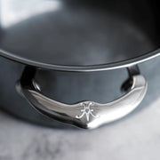 Close-up of the ergonomic handle on the Hestan NanoBond Cookware, 3qt Soup Pot, showcasing the embossed logo on its stainless-steel grip.