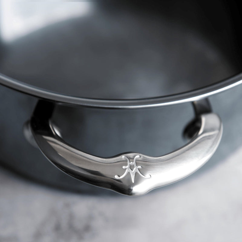 Close-up of the ergonomic handle on the Hestan NanoBond Cookware, 3qt Soup Pot, showcasing the embossed logo on its stainless-steel grip.