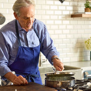 Man checks Hestan | Titanium Essential 5-Piece Cookware Set on stove, showcasing its durability and precision, in a contemporary kitchen setting.