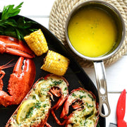 Seafood platter with lobster and grilled corn, highlighting the Hestan | Cookware .75qt Butter Warmer Pan, ideal for melting butter, featured in Athens Cooks' curated kitchen collection.