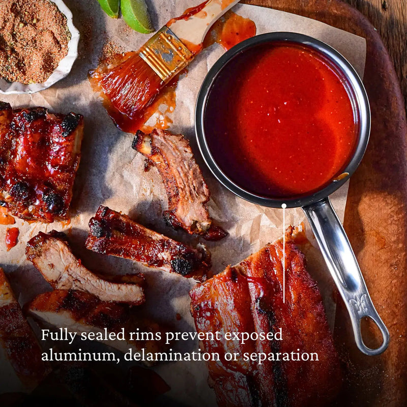 Hestan | Cookware, .75qt Butter Warmer Pan featured in a barbecue scene with ribs, BBQ sauce, and spice mix.