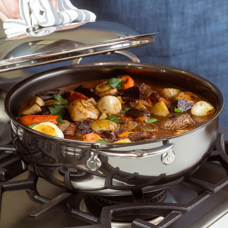 Hestan NanoBond Cookware 5qt Dutch Oven with dome lid on stove, showcasing a hearty stew with beef, vegetables, and herbs, highlighting its versatile cooking capabilities.