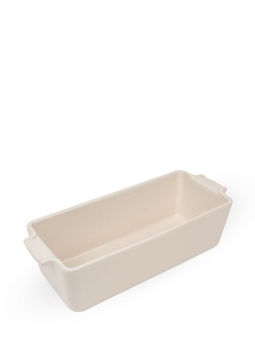 Peugeot | Appolia Loaf Pan: Cream-colored ceramic baking dish with flared handles, ideal for evenly cooking and presenting breads.