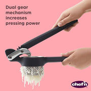 A person using the Chef'n Potato Ricer, pressing a white object, demonstrating its functionality.