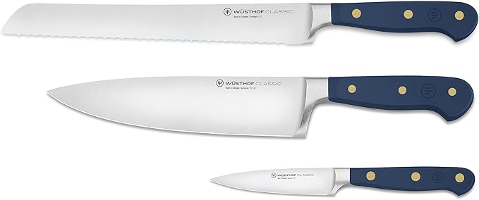 Wüsthof | Classic Wild Blueberry 3-Piece Starter Knife Set featuring a serrated bread knife, chef’s knife, and paring knife with dark-blue handles and brass rivets.