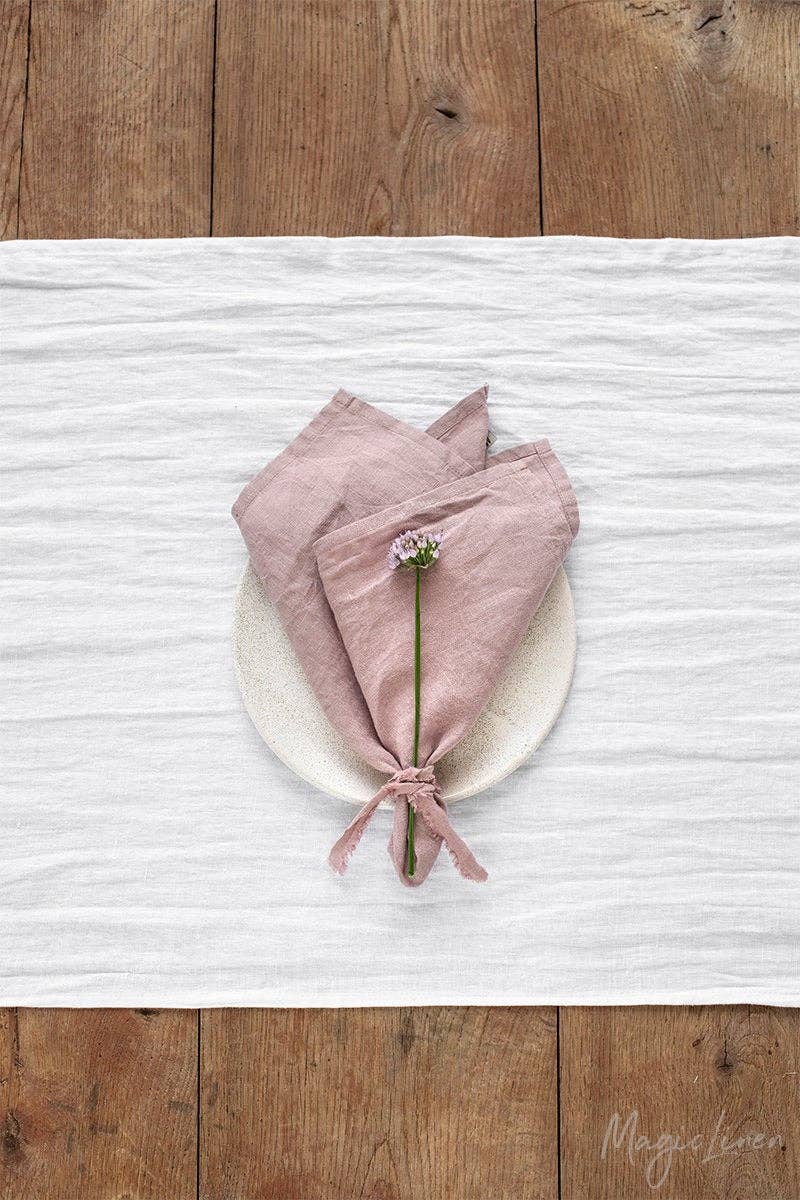 Set of 2 linen napkins on a wooden surface, featuring a floral accent, ideal for elegant table settings and decor.