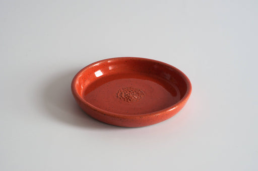 RachaelPots - Garlic Scraper: Coral, a hand-thrown ceramic dish with a speckled reddish-orange glaze, designed for quickly turning garlic into puree.