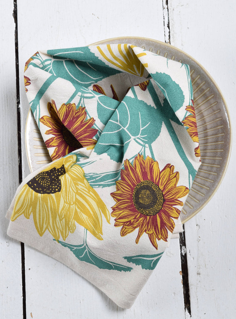 Hearth and Harrow - Sunflower Tea Towel - Organic Cotton - Oversized 30 x 30, displayed on a ceramic plate, ideal for enhancing any kitchen setting.