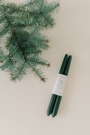 Mo&Co Home - Forest Green | Dipped Beeswax Taper Candles, handcrafted, dark-green, paired with a white label, on a light-beige surface, eco-conscious and air-purifying.