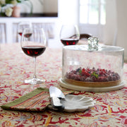 Couleur Nature - Noel Red & Green French Tablecloth enhances a dessert setting with intricate holiday patterns beneath a fruit tart and wine glasses.