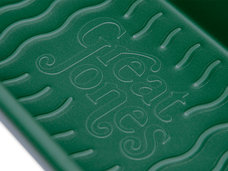 Great Jones | Breadwinner - Raspberry loaf pan with nonstick, nontoxic ceramic coating and unique wavy bottom for easy bread release, showcased in close-up detail.