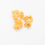 Poppy Hand | Crafted Popcorn - Pimento Cheese: Three pieces of cheese-coated popcorn, showcasing the Southern-inspired, savory flavor with non-GMO cheddar and a pimento kick.