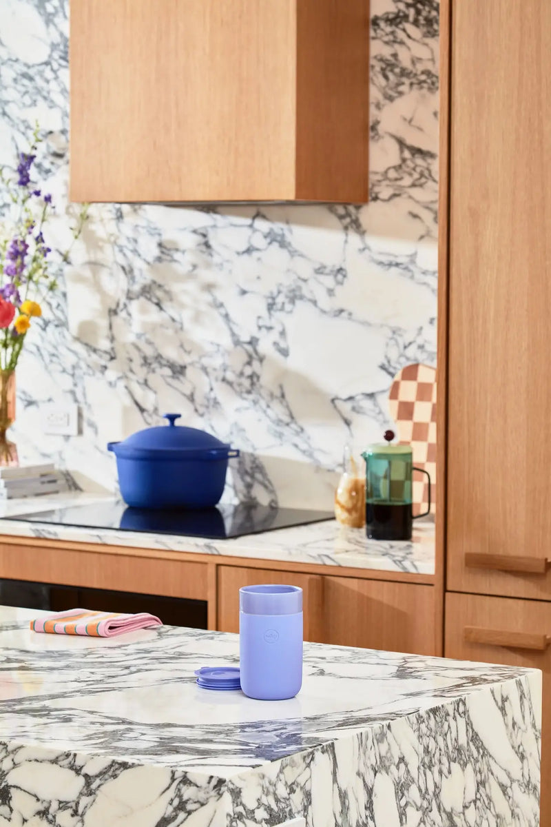 W&P - Reusable Ceramic Mug: Terrazzo Blush / 16 oz on a marble counter, featuring a splash-resistant lid and soft-touch silicone sleeve for easy sipping.