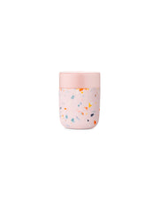 W&P - Reusable Ceramic Mug: Terrazzo Charcoal / 16 oz with white lid, designed for easy sipping and portability, featuring a pink and white container.