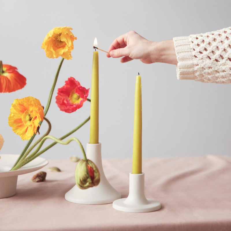 The Floral Society | Candle Holders, Grand, Matte White Tall, elegantly displayed with olive-green taper candles on a rose-pink cloth, exuding a modern, romantic ambiance.
