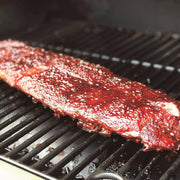 Southern Roots Sisters - Raspberry Chipotle Jam glazed ribs roasting on a grill, showcasing the jam's sweet and smokey flavor as a versatile barbecue sauce.