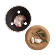 Emile Henry Garlic Pot with peeled garlic, bay leaves, and thyme, showcasing its ventilated design for freshness and elegance, ideal for Athens Cooks kitchen collections.