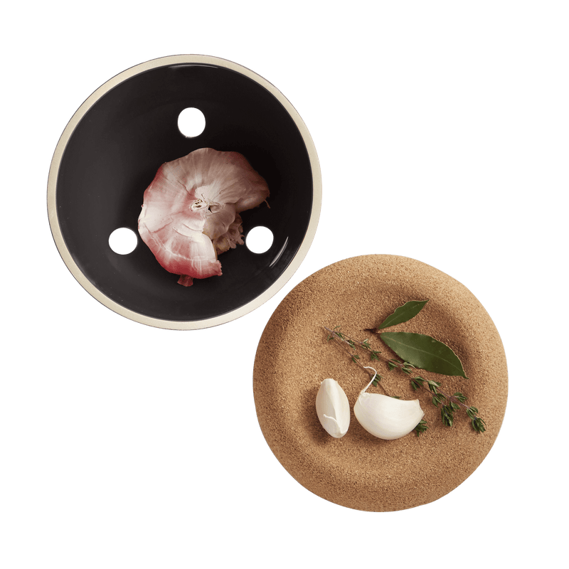 Emile Henry Garlic Pot with peeled garlic, bay leaves, and thyme, showcasing its ventilated design for freshness and elegance, ideal for Athens Cooks kitchen collections.