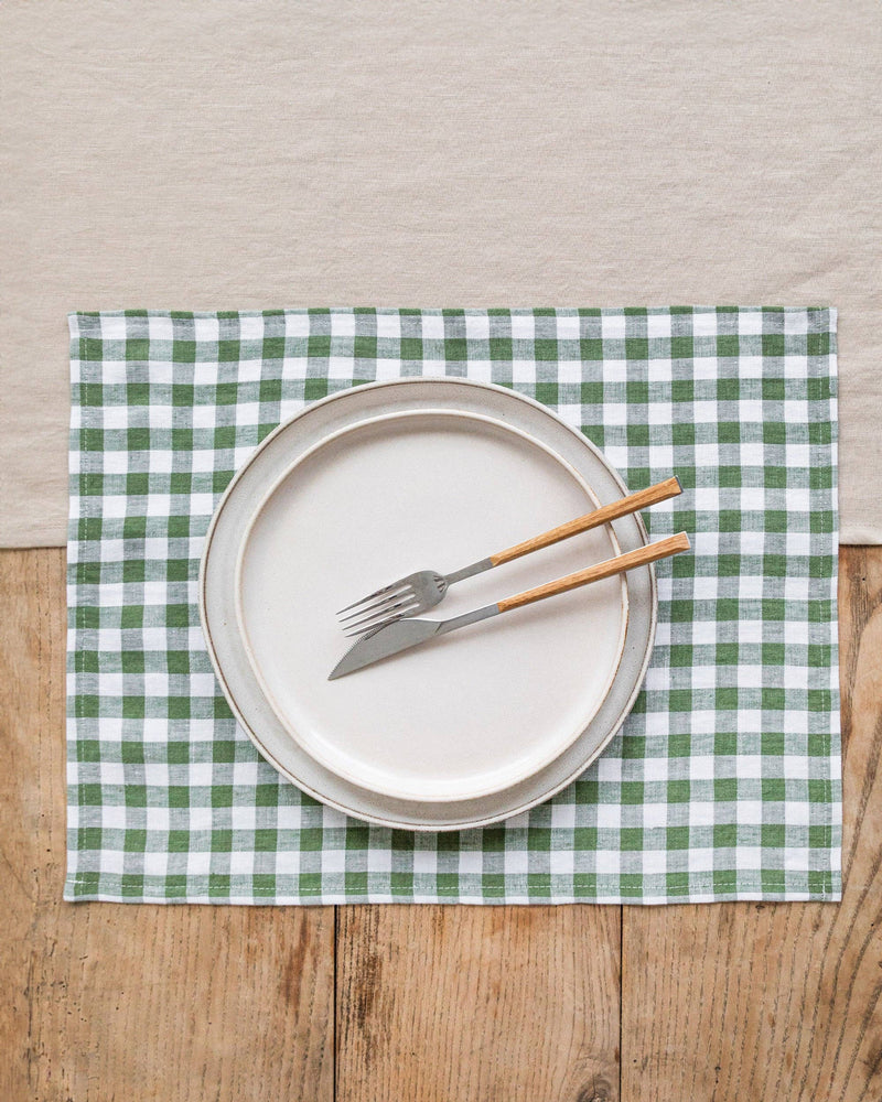 Forest green gingham linen placemat set of 2 with a fork and knife on a table, ideal for stylish dining from Athens Cooks.