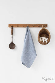 Linen tea towel hanging on a hook, accompanied by a basket and spoon, showcasing MagicLinen's absorbent, durable kitchen accessory from Athens Cooks.