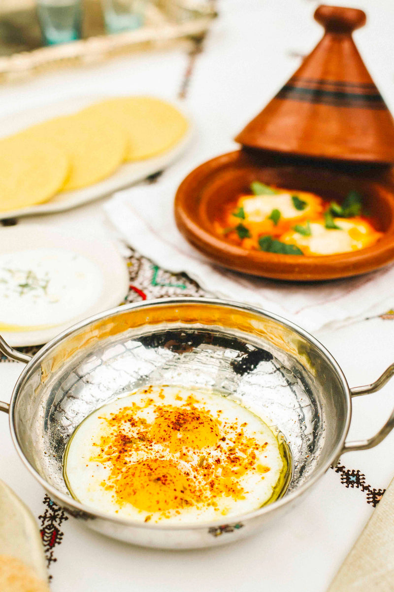 Villa Jerada - Aleppo - 60g spice enhances sunny-side-up eggs, adding complexity to a brunch spread with flatbreads and a tomato egg dish on an embroidered tablecloth.