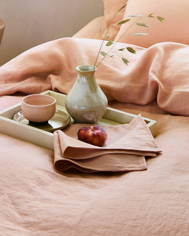 Linen tea towel displayed on a tray with a bowl and a vase, highlighting its texture and absorbency, ideal for kitchen use.