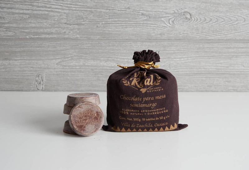 Verve Culture - Villa Real Mexican Hot Chocolate: Almond / Large - 10 Discs in an artisanal Oaxacan cloth pouch with stacked chocolate tablillas, perfect for crafting authentic hot chocolate.