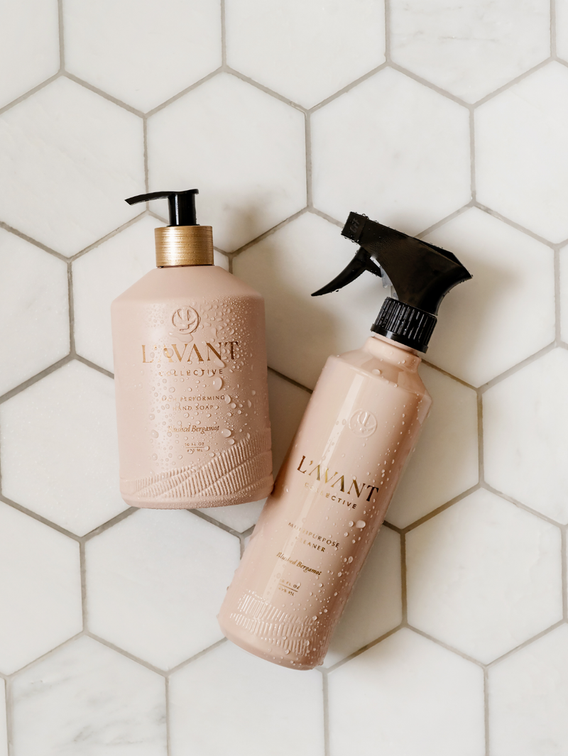 L'AVANT Collective - High Performing Hand Soap - Blushed Bergamot bottles on a tile surface, showcasing a blush pink glass bottle with pump and spray options.