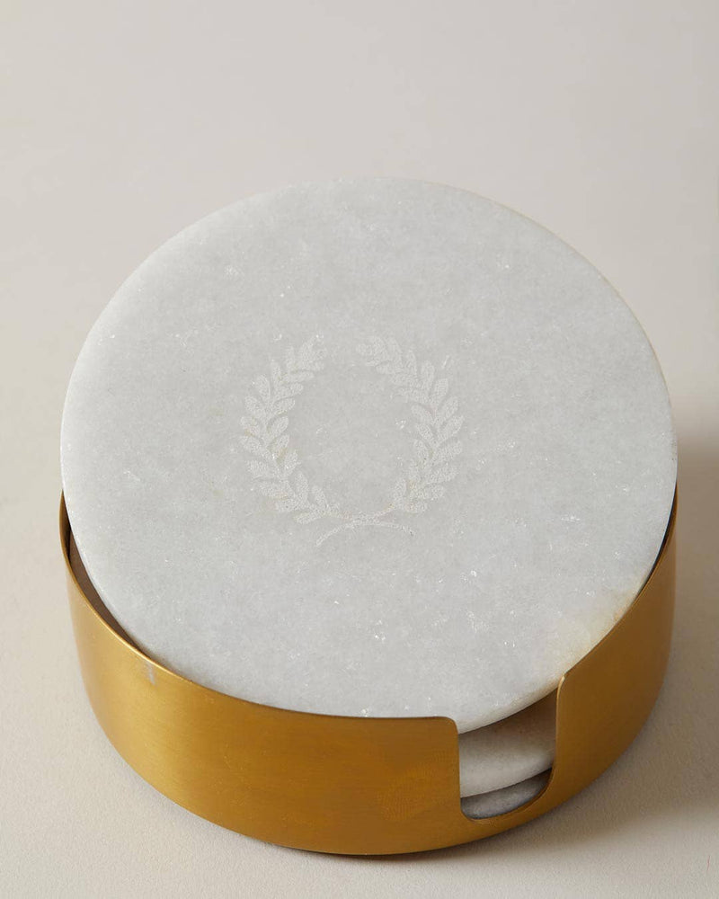 Farmhouse Pottery - Marble Laurel Coasters set in a brushed gold holder, featuring etched laurel motifs on white marble. Perfect for protecting surfaces elegantly.