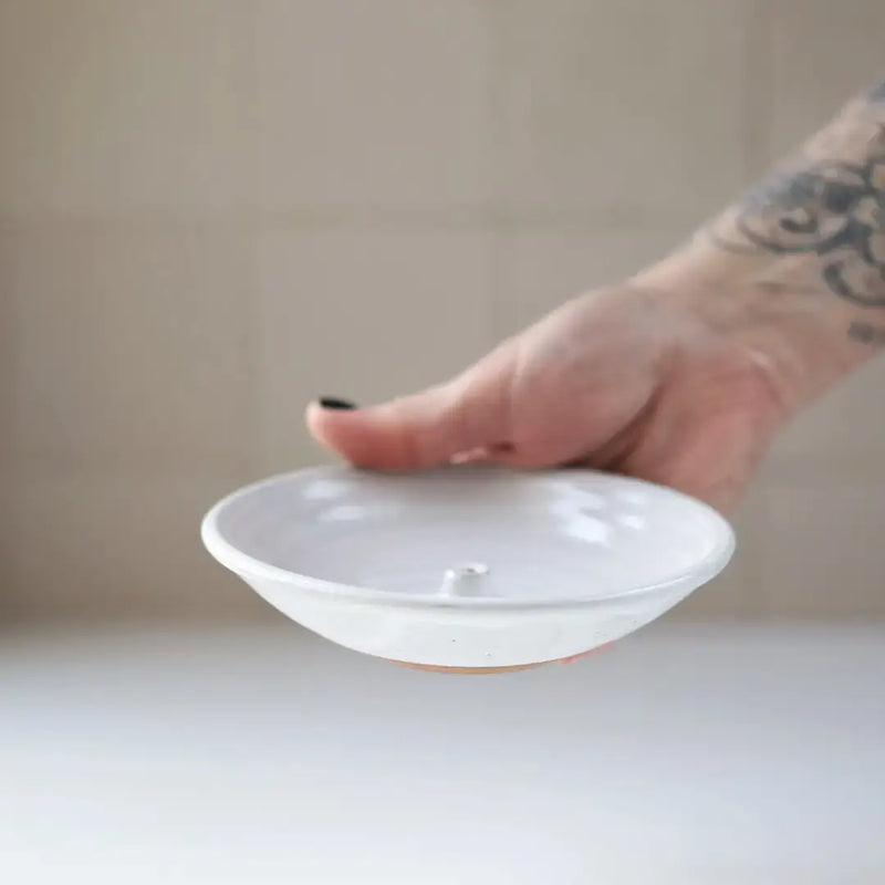 Gravesco Pottery Incense Burner, a shallow white ceramic dish with a central knob, held in hand, designed for catching incense ash.