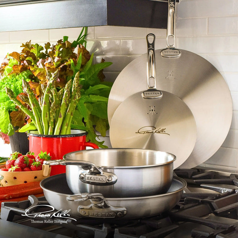 Hestan Provisions | Commercial Clad Stainless Steel Universal Lids, 8.5 Inches, on cooktop with sauté pan and skillet, surrounded by fresh produce and cookware.