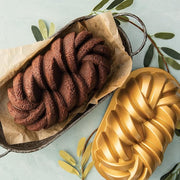 Nordic Ware | Braided Loaf Pan in metal, showcasing dual-strand design, perfect for detailed baking, seen alongside another loaf in a similar pan.