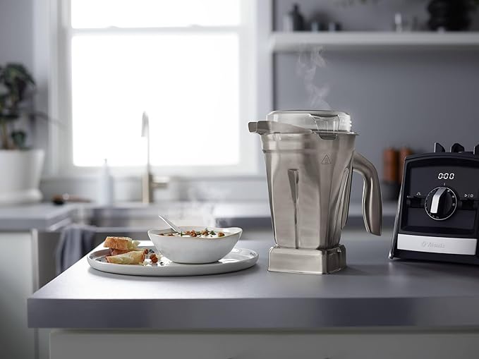 Vitamix | 48 oz Stainless Steel Container on a kitchen counter with a blender and a bowl of soup, ideal for professional-grade blending.