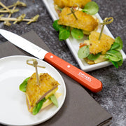 Opinel | Essential Paring Knife, Tangerine, displayed with elegant hors d’oeuvres on a platter, highlighting precision and style for kitchen tasks.