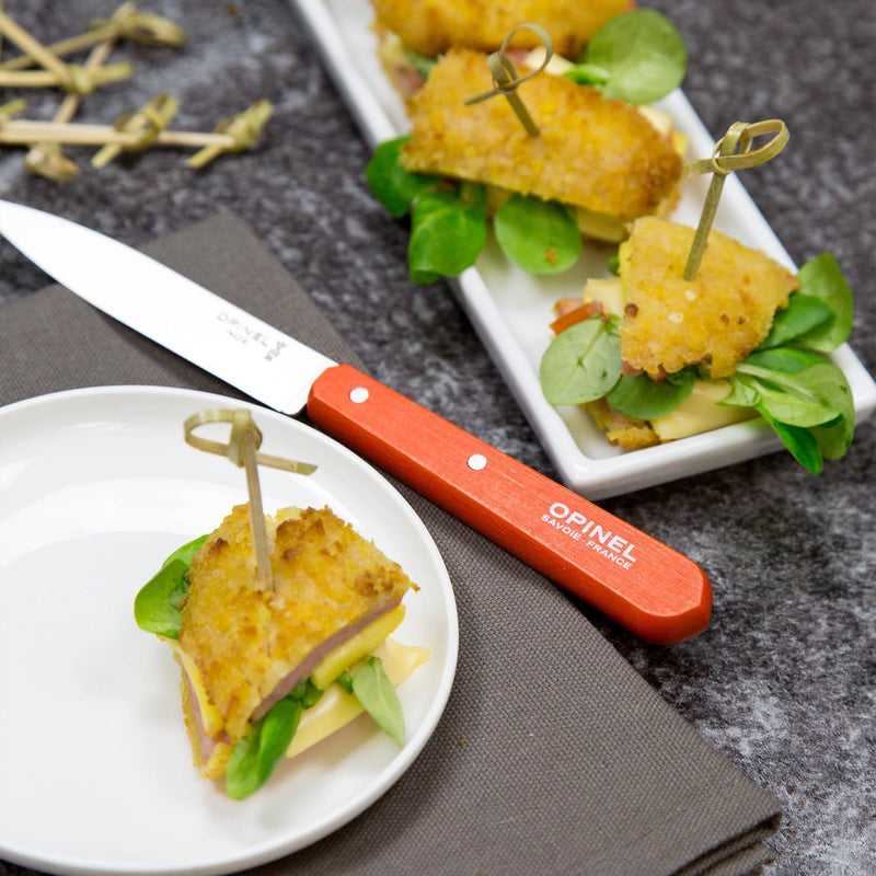 Opinel | Essential Paring Knife, Tangerine, displayed with elegant hors d’oeuvres on a platter, highlighting precision and style for kitchen tasks.