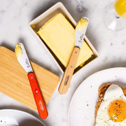 Opinel | Essential Spreading Knife, Skyblue, displayed with a butter dish and toast, showcases its versatility in spreading butter, perfect for breakfast settings.