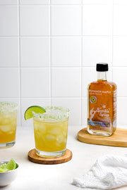 Runamok | Mini Sparkle Syrup on a coaster, presented in a glass with ice and lime, capturing a cocktail essence.