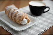 Fantes | Mini Cannoli Forms on a table beside a pastry and coffee, showcasing their use for crafting crispy homemade cannoli shells.