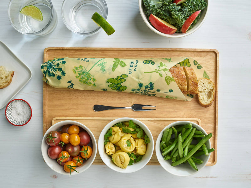 Bee's Wrap - Assorted 3 Pack - Herb Garden, Plant Based Wax, displayed on a tray with vegetables and a glass of water, showcasing its versatile kitchen use.