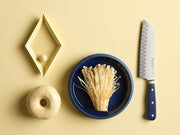 Wüsthof Classic 7 Hollow Edge Santoku knife displayed with a bowl of mushrooms and a donut, highlighting its versatility in kitchen tasks.