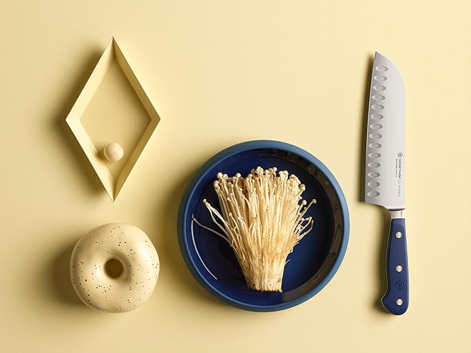 Wüsthof Classic 7 Hollow Edge Santoku knife displayed with a bowl of mushrooms and a donut, highlighting its versatility in kitchen tasks.
