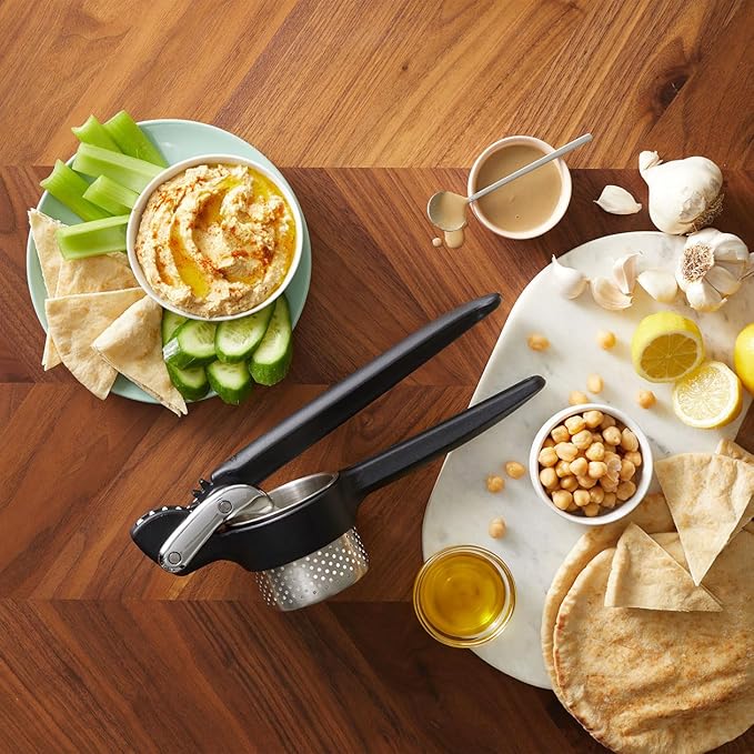 Chef'n Potato Ricer on a table alongside a bowl of hummus with cucumbers, perfect for creating smooth mashed potatoes.