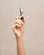 L'Atelier du Vin - USA - Pourer and aerator - POURER-LEAF held in hand, featuring a polished leaf top and rubber base for wine oxygenation and controlled pouring.