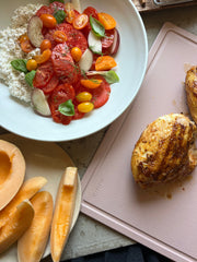 The MK Free Board, Ocean, showcasing its eco-friendly design, supports a summertime meal prep with roasted chicken and tomato salad, emphasizing safe and efficient kitchen use.