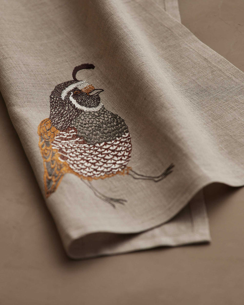 Coral & Tusk - Quail Tea Towel features exquisite quail embroidery on soft-beige linen, perfect for enhancing kitchen decor with nature-inspired elegance.